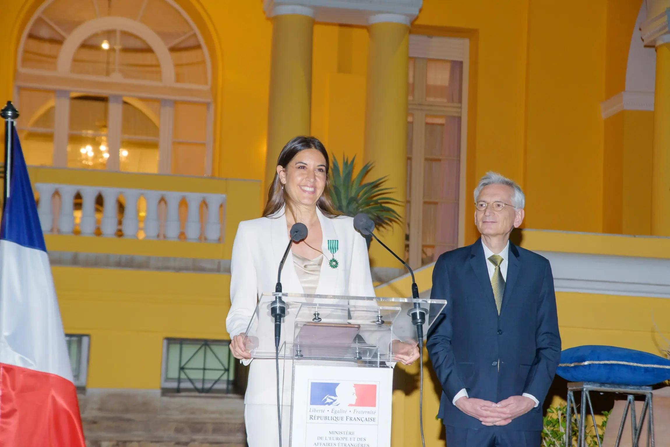 Farrah El Dibany speaking at an official French diplomatic ceremony in a historic venue, highlighting cultural diplomacy and international cooperation.